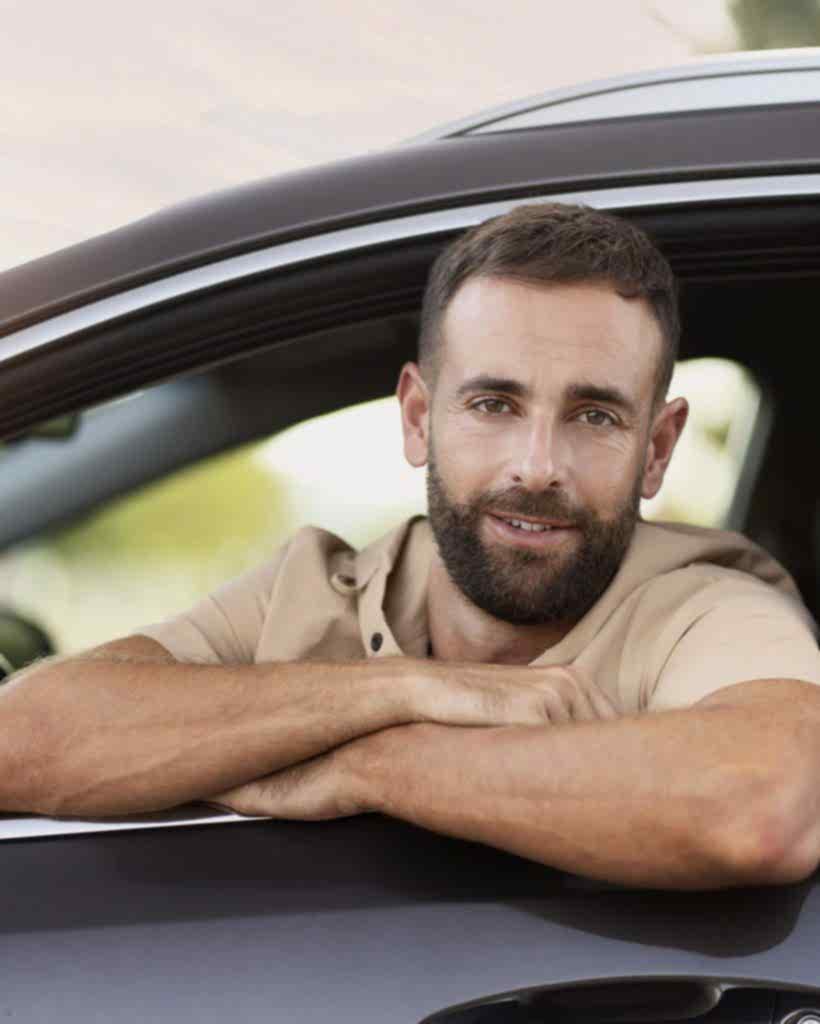 smiling-latin-driving-sitting-in-car-looking-at-ca-2023-11-27-05-09-07-utc